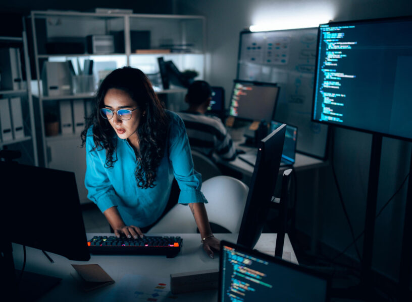 Hispanic Female Software Developer Coding at Night in Dark Tech Office