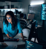 Hispanic Female Software Developer Coding at Night in Dark Tech Office